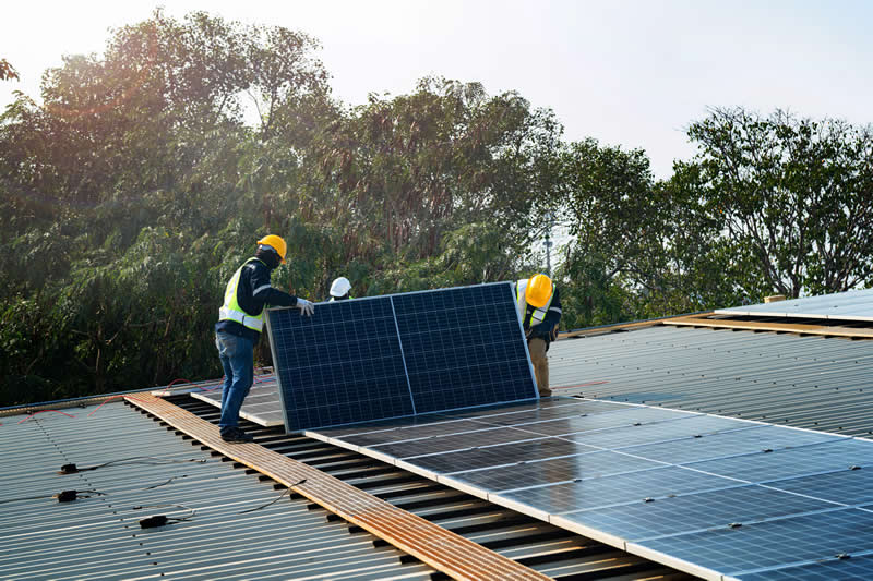 Worker Technicians are working to construct solar panels system on roof.