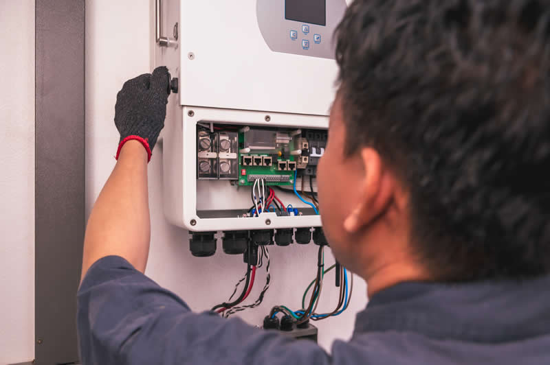 solar engineer with electric meter checking with hybrid solar inverter